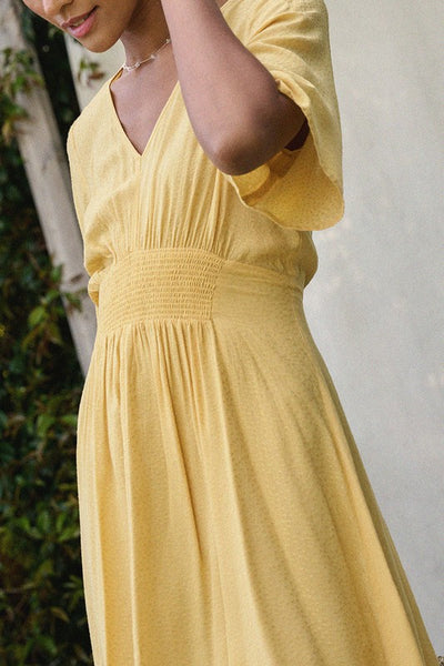 Wear a bit of sunshine with this beautiful yellow smocked mini dress. Featuring a v neckline, smocked waistline, and textured material. Pair with a classic denim jacket for cooler nights. Product Details: 100% Rayon 1/2 Sleeve Smock flared waist Mini length - above the knee Lined from waist down Fit and flare silhouette