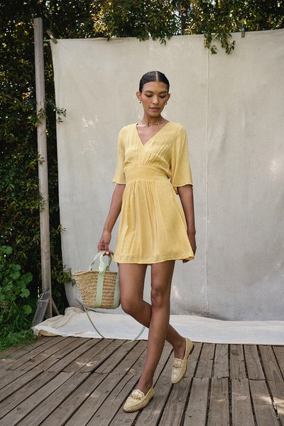 Wear a bit of sunshine with this beautiful yellow smocked mini dress. Featuring a v neckline, smocked waistline, and textured material. Pair with a classic denim jacket for cooler nights. Product Details: 100% Rayon 1/2 Sleeve Smock flared waist Mini length - above the knee Lined from waist down Fit and flare silhouette