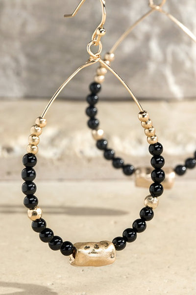 Dazzling teardrop earrings with a natural black stones and hammered metal gold beads. Product Details: Dangle drop fish hook design Approximately 2" long x 1" wide Natural stone, steel
