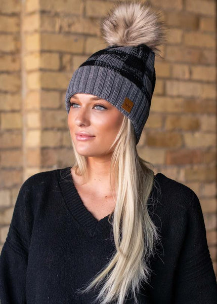 Classic grey and black buffalo plaid fleece lined knit hat with pom detail. Perfect color combination to go with all your winter gear! Product Details: Knit hat Fleece lined Large faux fur pom