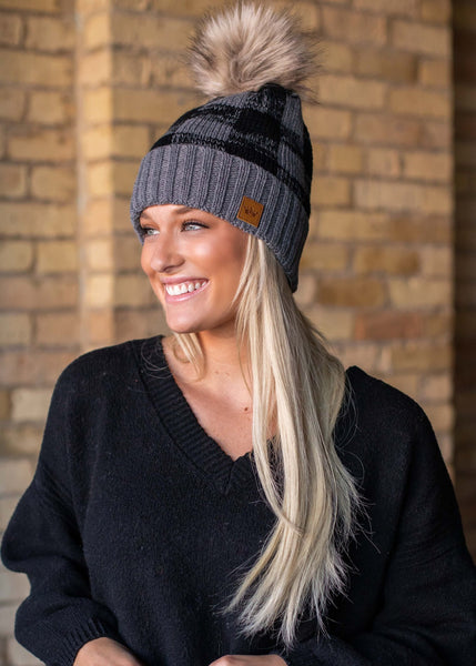 Classic grey and black buffalo plaid fleece lined knit hat with pom detail. Perfect color combination to go with all your winter gear! Product Details: Knit hat Fleece lined Large faux fur pom
