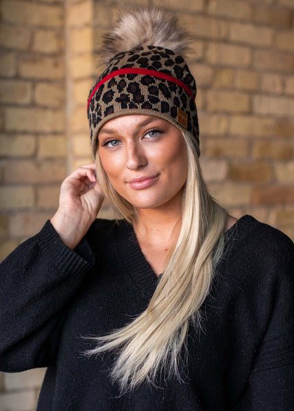 Stand out in this leopard pattern fleece lined knit hat. The red stripe detail and faux fur pom accent takes this winter hat up a notch.