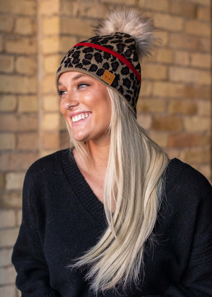 Stand out in this leopard pattern fleece lined knit hat. The red stripe detail and faux fur pom accent takes this winter hat up a notch.