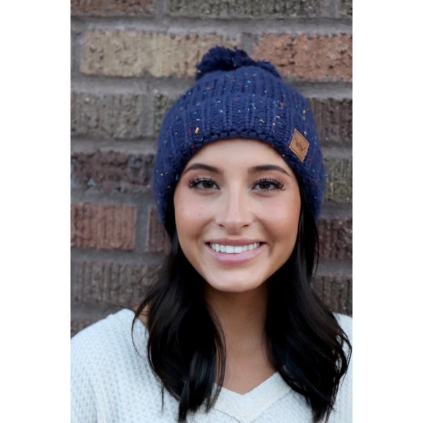 Keep your melon warm in this fleece lined navy speckled hat. Featuring a fun pom pom at the top and attractive large braided knit pattern. Product Details: 90% Acrylic, 10% Polyester, Lining 100% Polyester Fold down cuff Comfy fleece lining