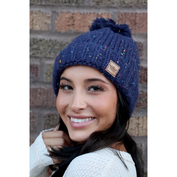 Keep your melon warm in this fleece lined navy speckled hat. Featuring a fun pom pom at the top and attractive large braided knit pattern. Product Details: 90% Acrylic, 10% Polyester, Lining 100% Polyester Fold down cuff Comfy fleece lining