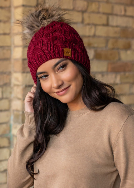 This stunning wine color cable knit fleece lined hat with keep your head warm and stylish! Product Details: 100% Acrylic, Lining 100% Polyester Knit hat Comfy fleece lining Faux fur pom accent