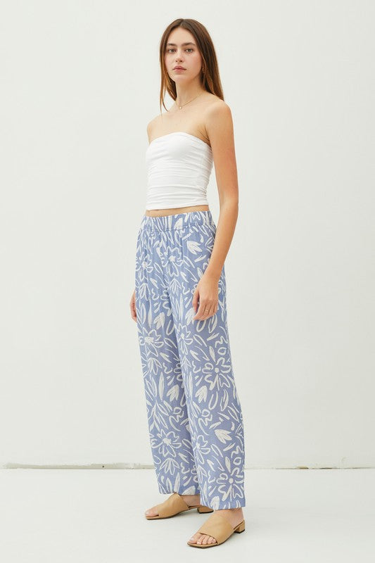 Glide through your day with ease and style in our Slate Flower Print Pants! The lightweight, double-lined fabric and elastic waistband provide ultimate comfort, while the ankle length and high waist give a flattering fit. With a breezy wide leg and convenient pockets, these pants are a delight!  Product Details:   85% Rayon, 15% Nylon Ankle length Wide leg High waist Lined to upper thigh Inseam: 27", Rise 12 1/2" Model is wearing a small