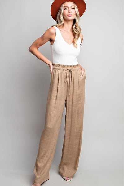 Indulge in the ultimate comfort and style with our Coco Linen Wide Leg Pants. These high waisted pants are designed with a smocked waist and waist tie for a flattering fit, while the side pockets add convenience. Perfect for both casual and dressy occasions, these pants will elevate your wardrobe.  Product Details:  65% Rayon, 35% Linen Model is 5'8" and wearing a small