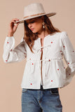 Fall in love with the romantic charm of this ivory blouse, adorned with delicate red heart embroidery that adds a playful pop of color. Featuring an elegant front-tie detail and feminine puff sleeves, this top strikes the perfect balance between sweet and sophisticated. The lightweight fabric drapes beautifully, making it ideal for date nights, casual outings, or festive occasions. Pair it with your favorite jeans, skirts, or tailored trousers to create a look that’s effortlessly chic and full of love!