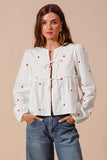 Fall in love with the romantic charm of this ivory blouse, adorned with delicate red heart embroidery that adds a playful pop of color. Featuring an elegant front-tie detail and feminine puff sleeves, this top strikes the perfect balance between sweet and sophisticated. The lightweight fabric drapes beautifully, making it ideal for date nights, casual outings, or festive occasions. Pair it with your favorite jeans, skirts, or tailored trousers to create a look that’s effortlessly chic and full of love!