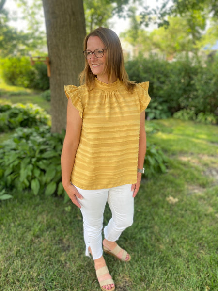 You need to add our Maddy Ruffle Top to your wardrobe! This playful piece features a high neck band, flouncy ruffle sleeves, and a tie and keyhole detail in the back. This stunning mustard color pairs well with white or classic denim.   Product Details:  Stripe burn out woven fabric Flouncy ruffle short sleeves Tie and keyhole back High neck