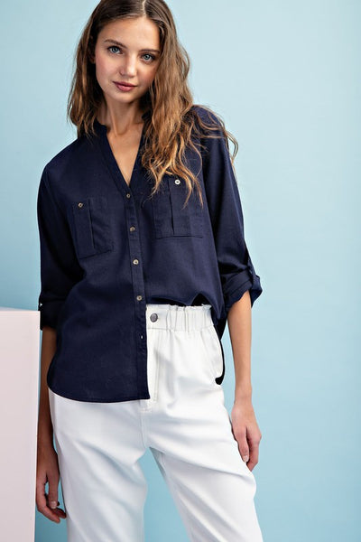 This soft washed navy long sleeve top is a wardrobe essential with its versatile button down front, notched neckline, and buttoned cuffs. The rounded bottom hem creates two side slits for added style. Perfect transition piece into warmer weather.  Product Details:  100% Cotton