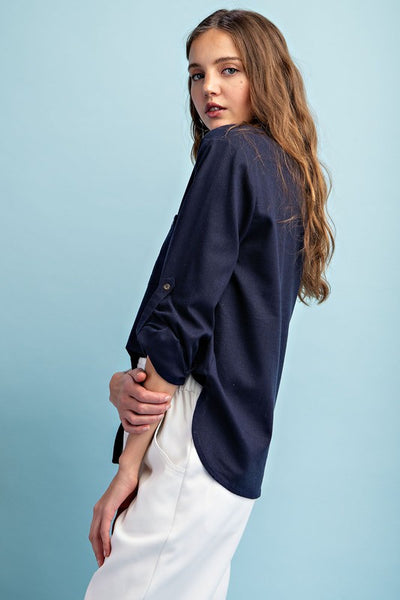 This soft washed navy long sleeve top is a wardrobe essential with its versatile button down front, notched neckline, and buttoned cuffs. The rounded bottom hem creates two side slits for added style. Perfect transition piece into warmer weather.  Product Details:  100% Cotton