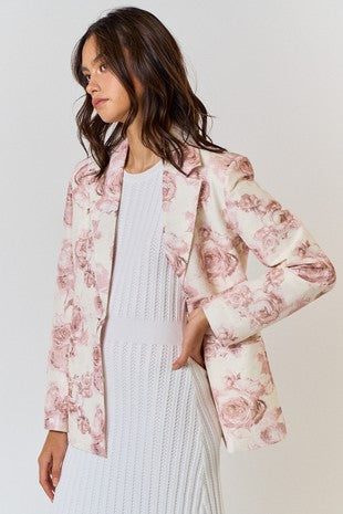 Indulge in the beautiful and romantic style of our Floral Print Blazer. The classic silhouette is elevated by a delicate pink and ivory print, adding a touch of elegance to any outfit. With functional pockets and a lined interior, this blazer also offers practicality in addition to its stylish charm.  Product Details:  95% Polyester, 5% Spandex Lining 100% Rayon