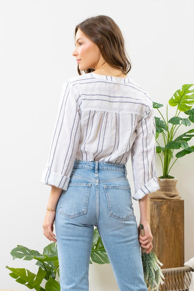 Feel carefree in this airy blue striped top. Featuring a split v-neckline with button detail, along with 3/4 roll tab sleeves. A warm weather approved top!  Product Details:   99.5% Cotton, .5% Spandex  Lightweight Sheer V-neckline with button detail 3/4 sleeves Roll tab sleeves