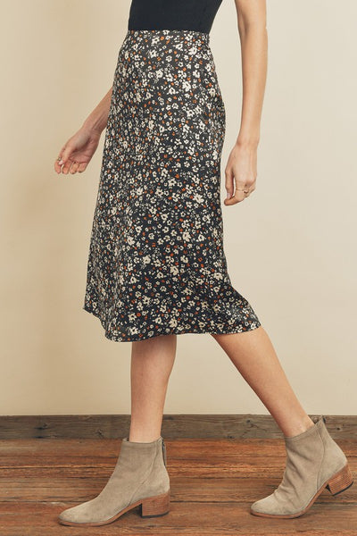 Fresh, fun, floral printed midi skirt. Featuring a silky black satin fabric with an elastic waistband on the back and a hidden back zipper closure.  Product Details:  100% Polyester Model is 5'9" and wearing size Small.