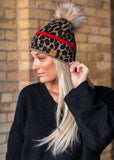 Stand out in this leopard pattern fleece lined knit hat. The red stripe detail and faux fur pom accent takes this winter hat up a notch. 