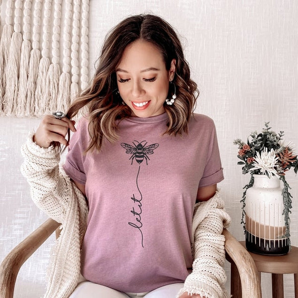 Let your top do the talking ! The Let It Bee shirt is a fan favorite and a great addition to your every day wardrobe. This cutie comes in colors white and orchid. Product Details:  Unisex Cut Tee (Bella + Canvas brand top) Hand screen printed in the US Cotton & Poly Blend Machine Wash